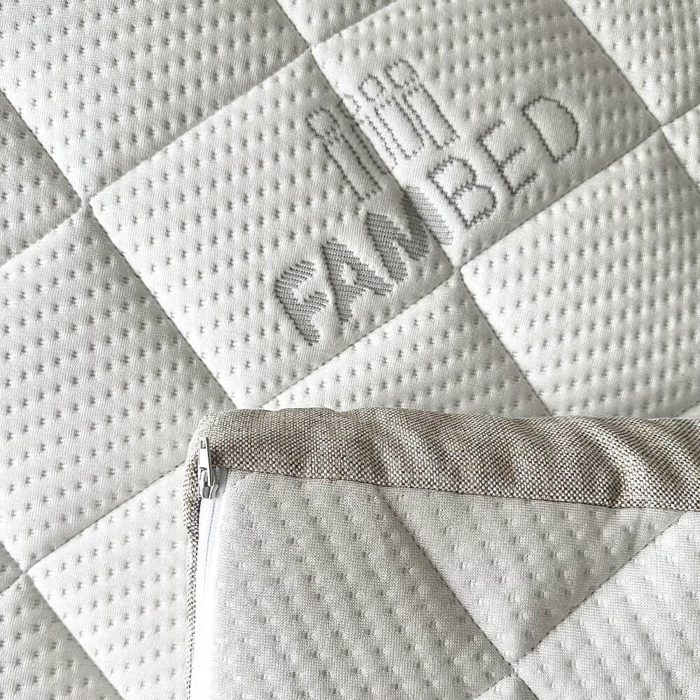Close-up of the mattress topper's quilted white cover with a woven FAMBED logo