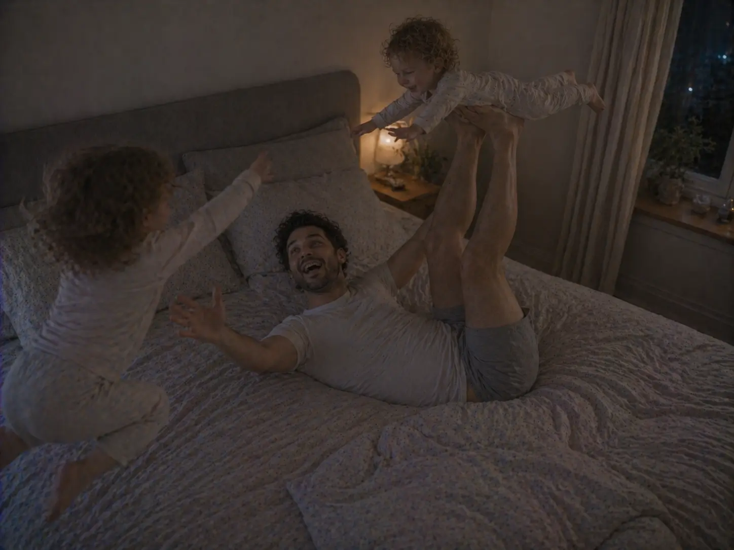 A father playing aeroplanes with one child on the bed while the other jumps beside them